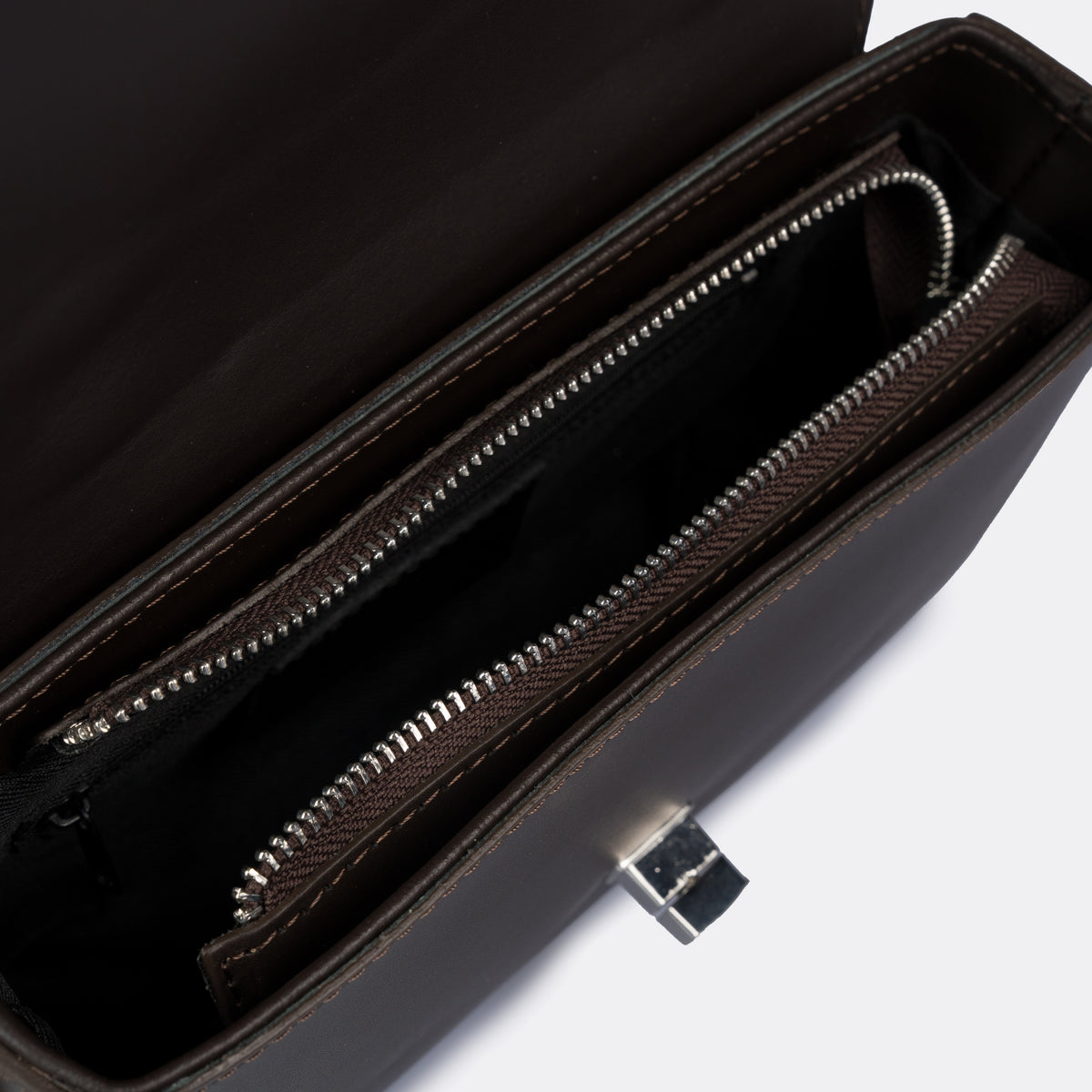 Compact brown top-handle bag in Pelle Ruga leather with silver-tone turn-lock bar, the Capri